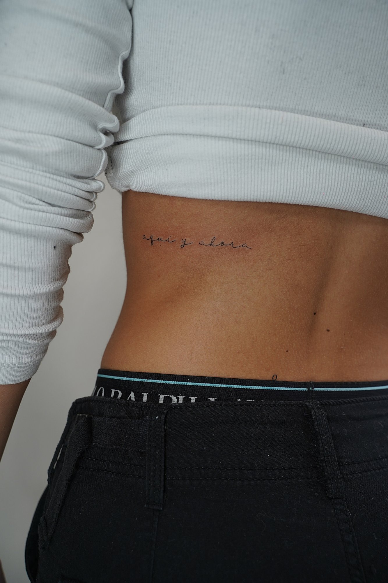 Tatuaje de frase aqui ahora maquina en zona desconocida, línea fina
