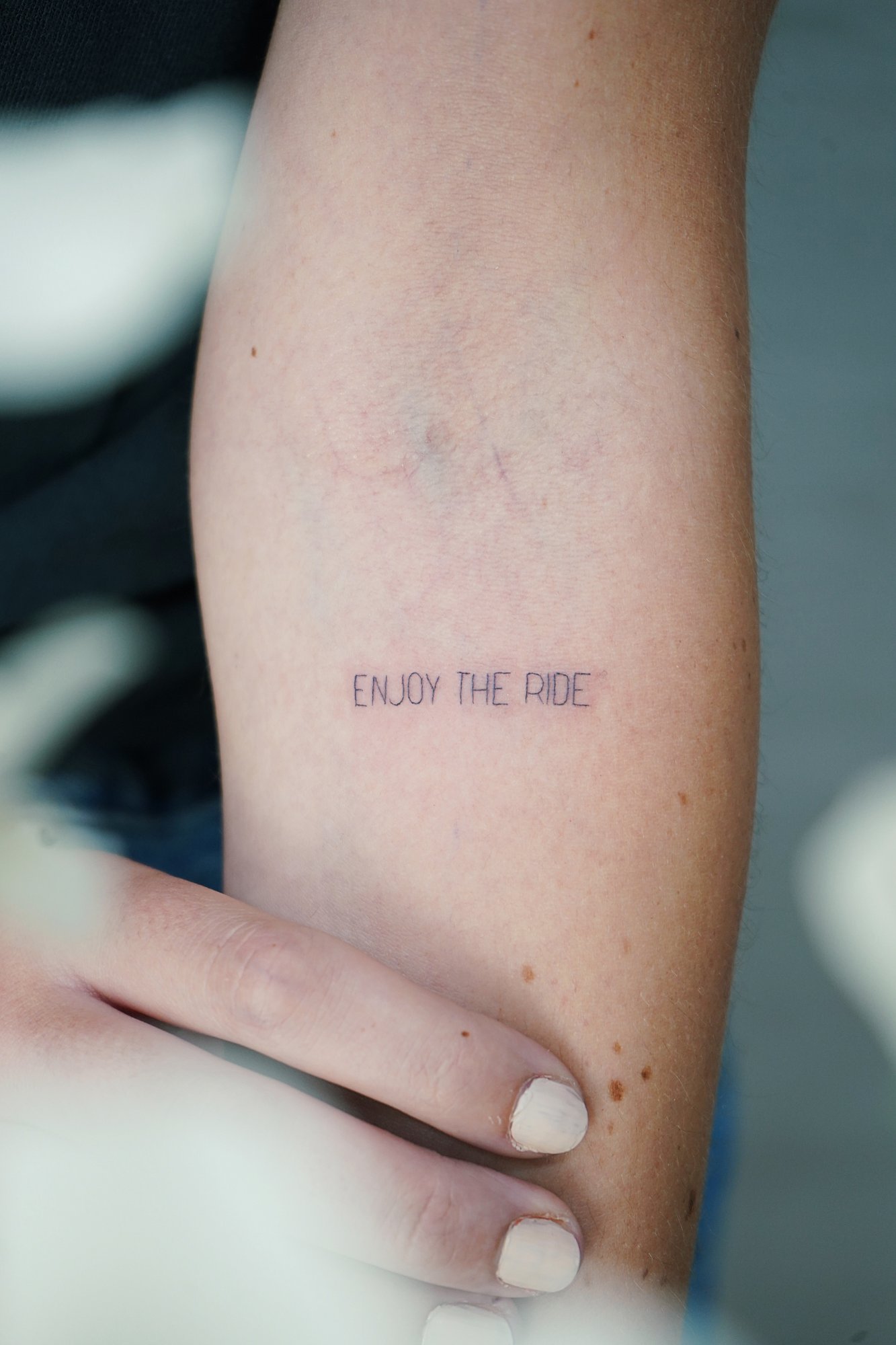 Tatuaje de frase enjoy the ride en zona desconocida, línea fina