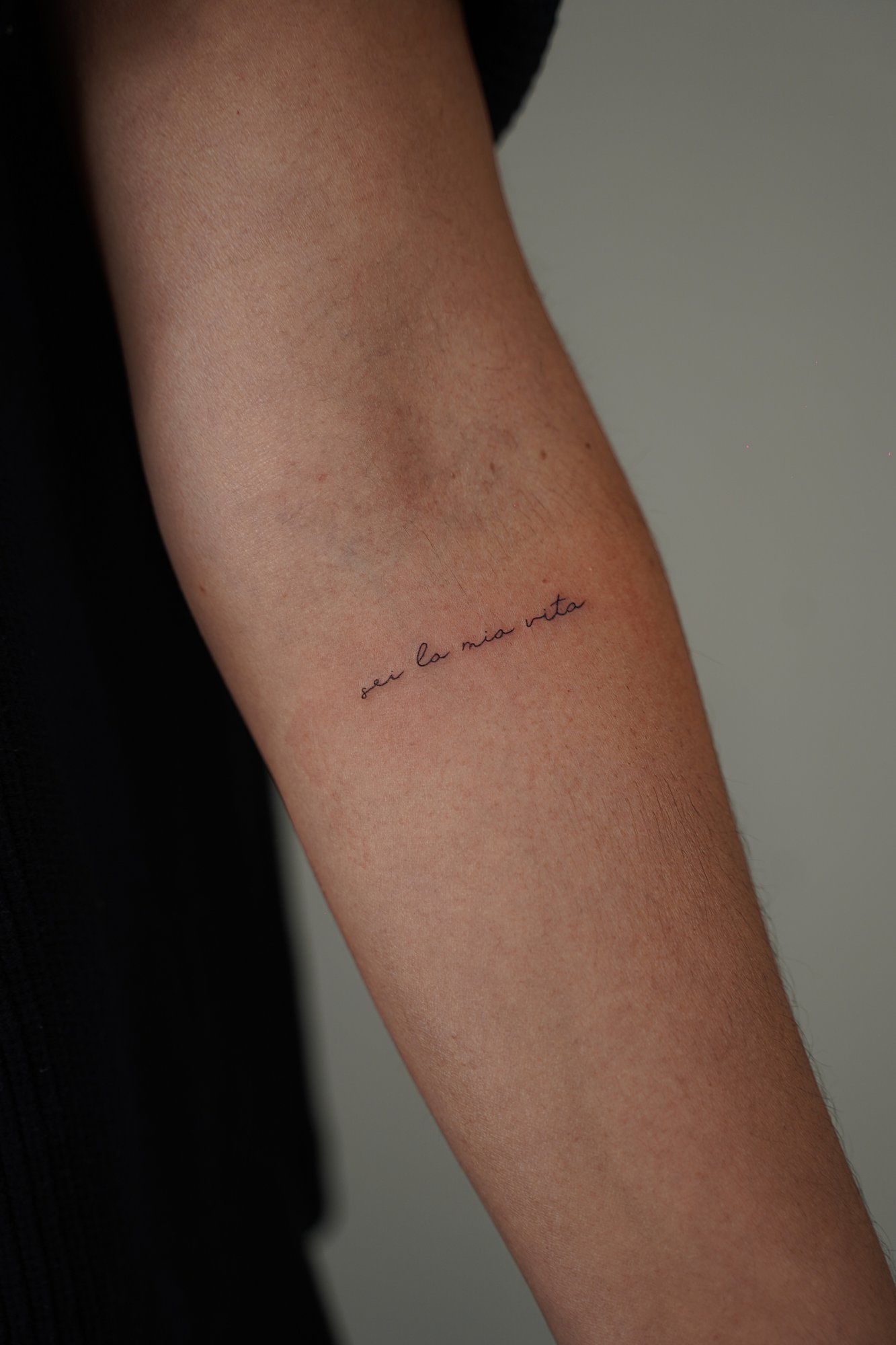 Tatuaje de frase italiana en zona desconocida, línea fina