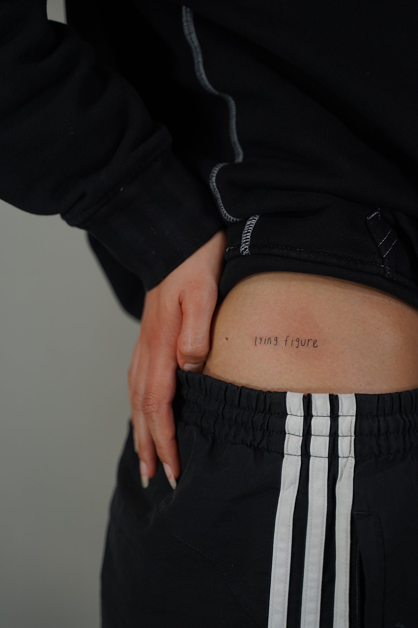 Tatuaje de frase lying figure en cadera, línea fina