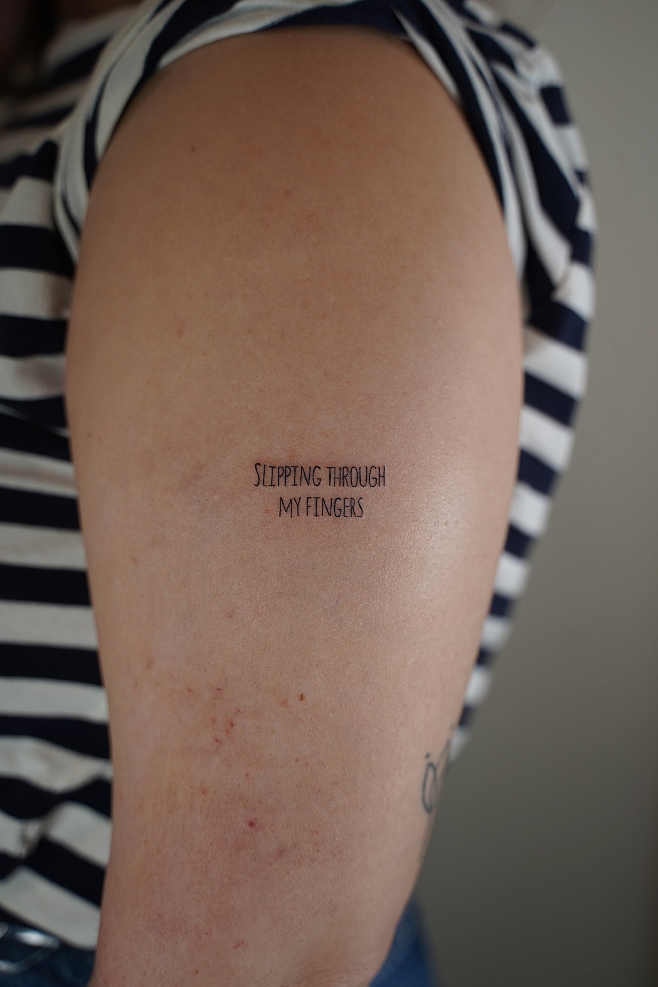 Tatuaje de frase mayuscula en zona desconocida, línea fina