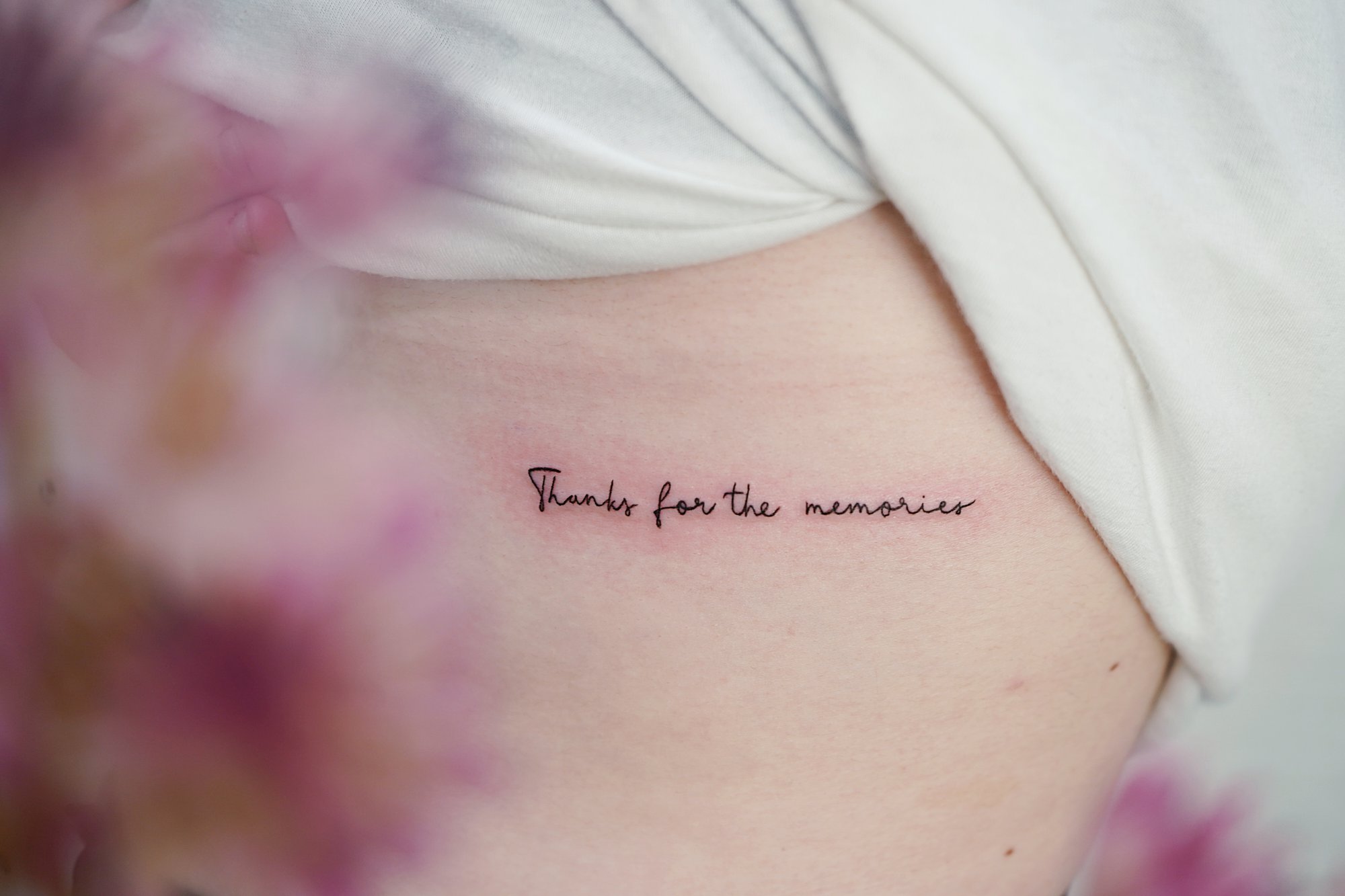 Tatuaje de frase thanks en costilla, línea fina