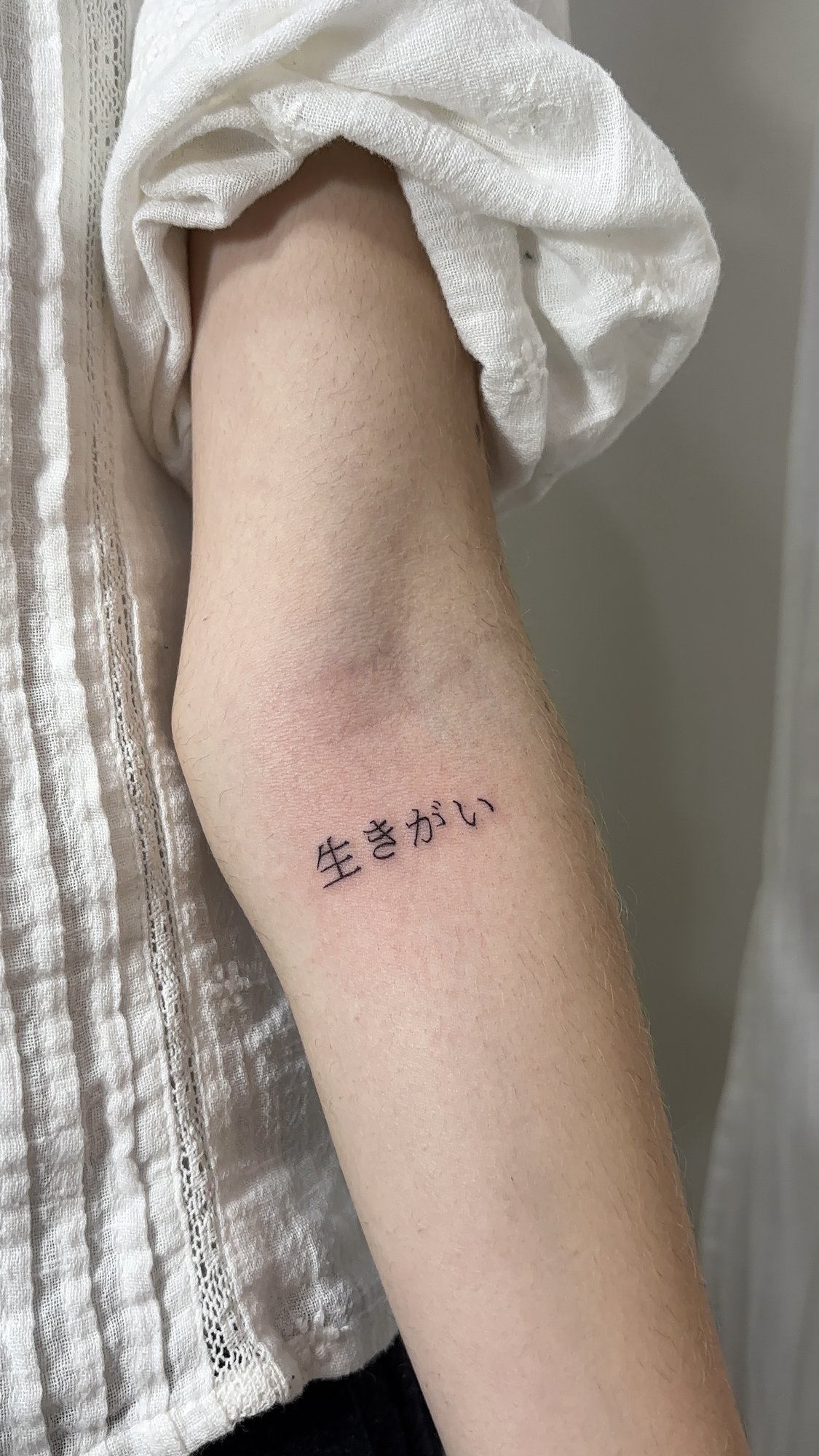 Tatuaje de ikigai japones escritura en antebrazo, línea fina