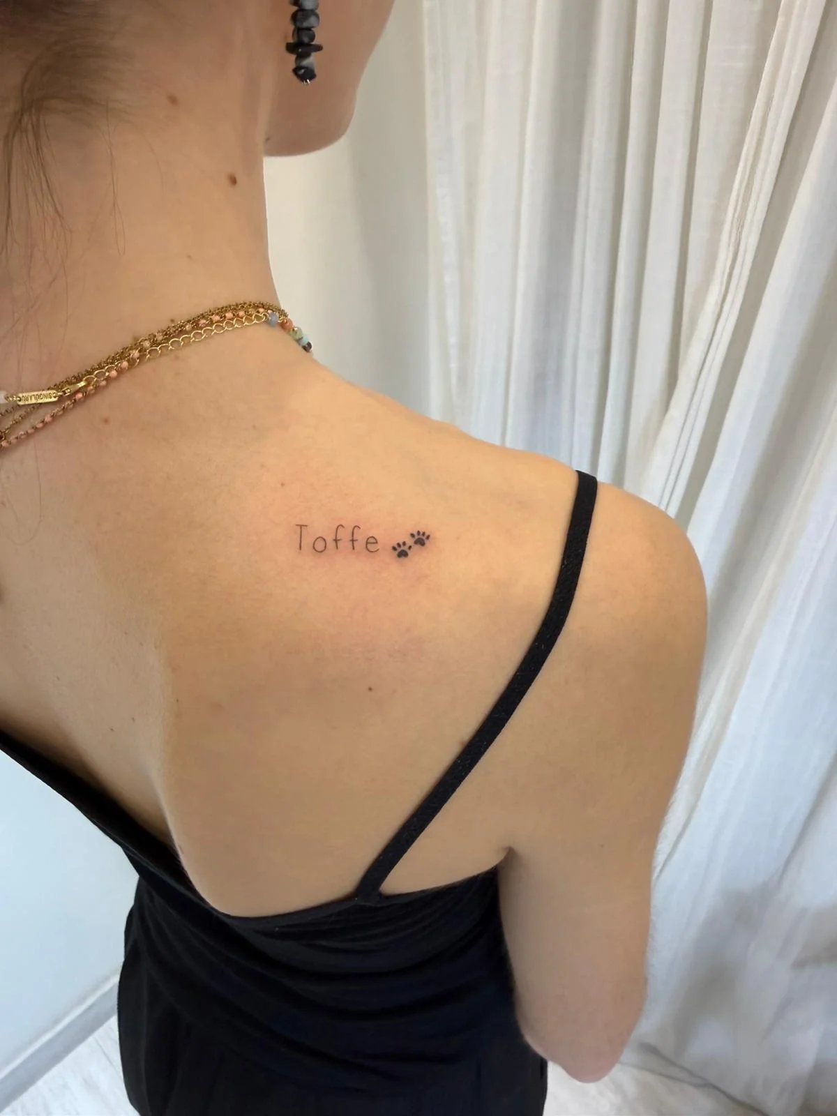 Tatuaje letras-frases nombre con huellas patas espalda