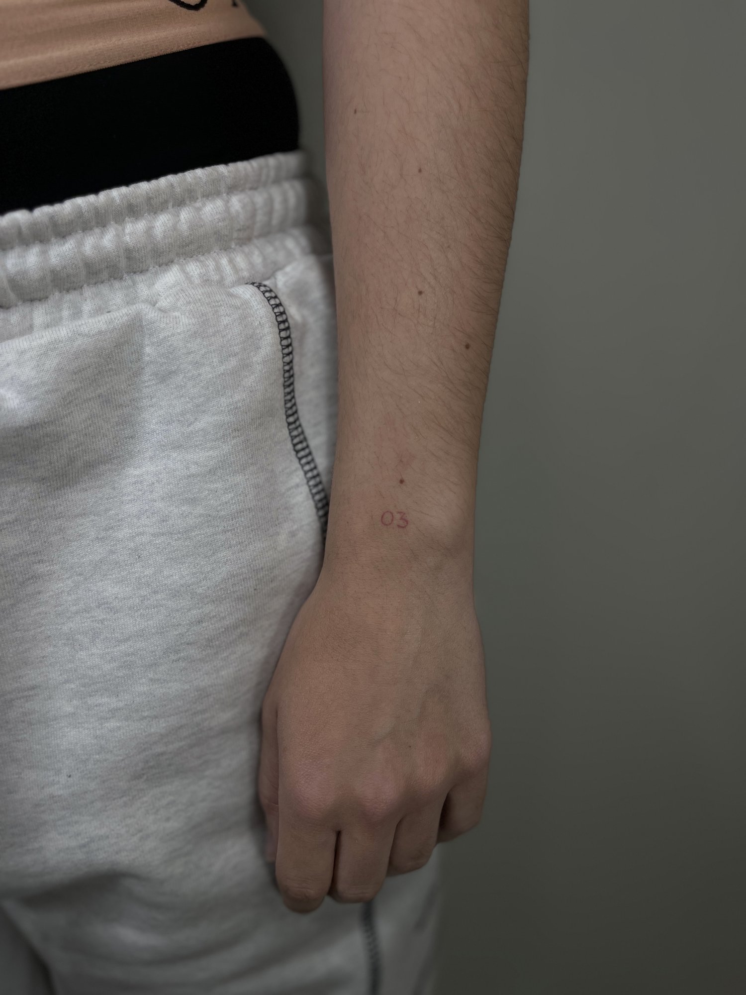 Tatuaje de numero 03 minimalista en muneca, línea fina