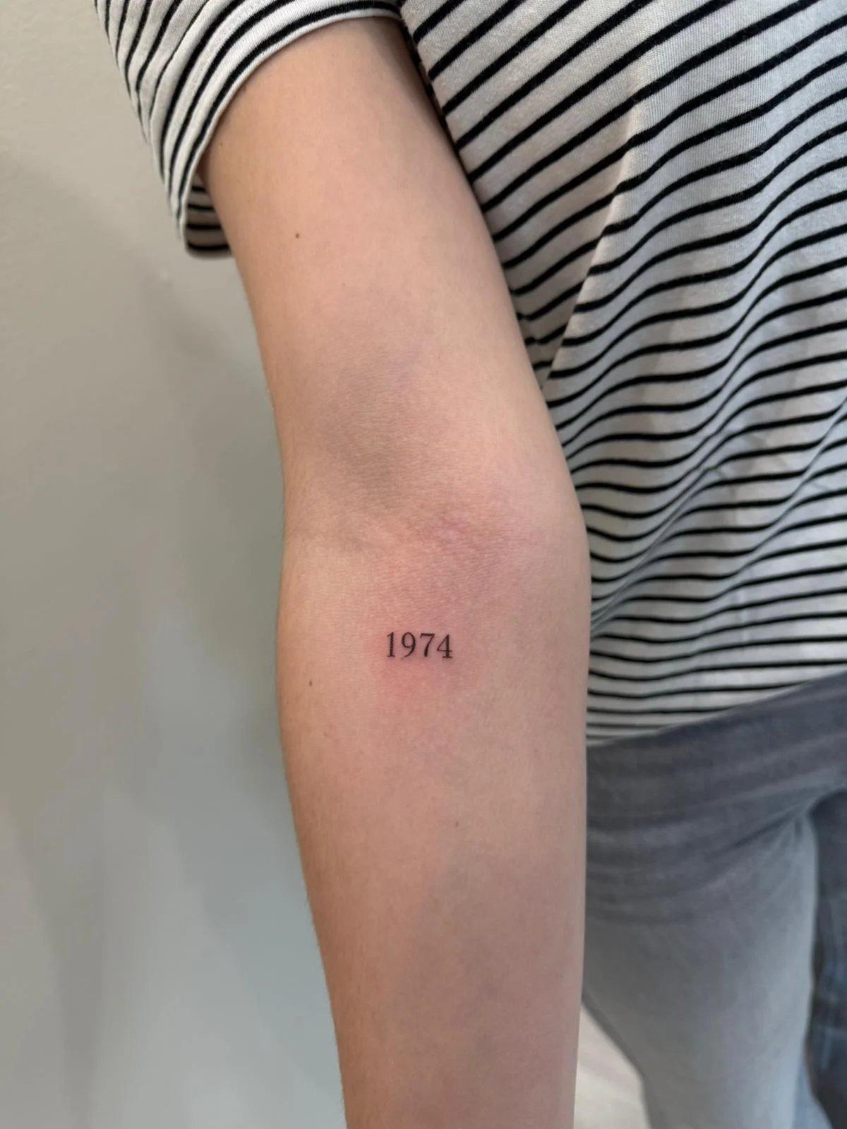 Tatuaje letras-frases numero fecha 1974 antebrazo