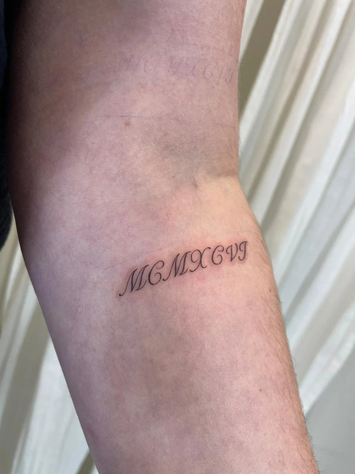 Tatuaje letras-frases numeros romanos cursiva antebrazo