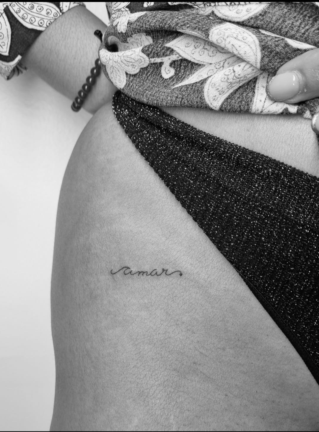 Tatuaje de palabra amar cursiva delicada en muslo, línea fina