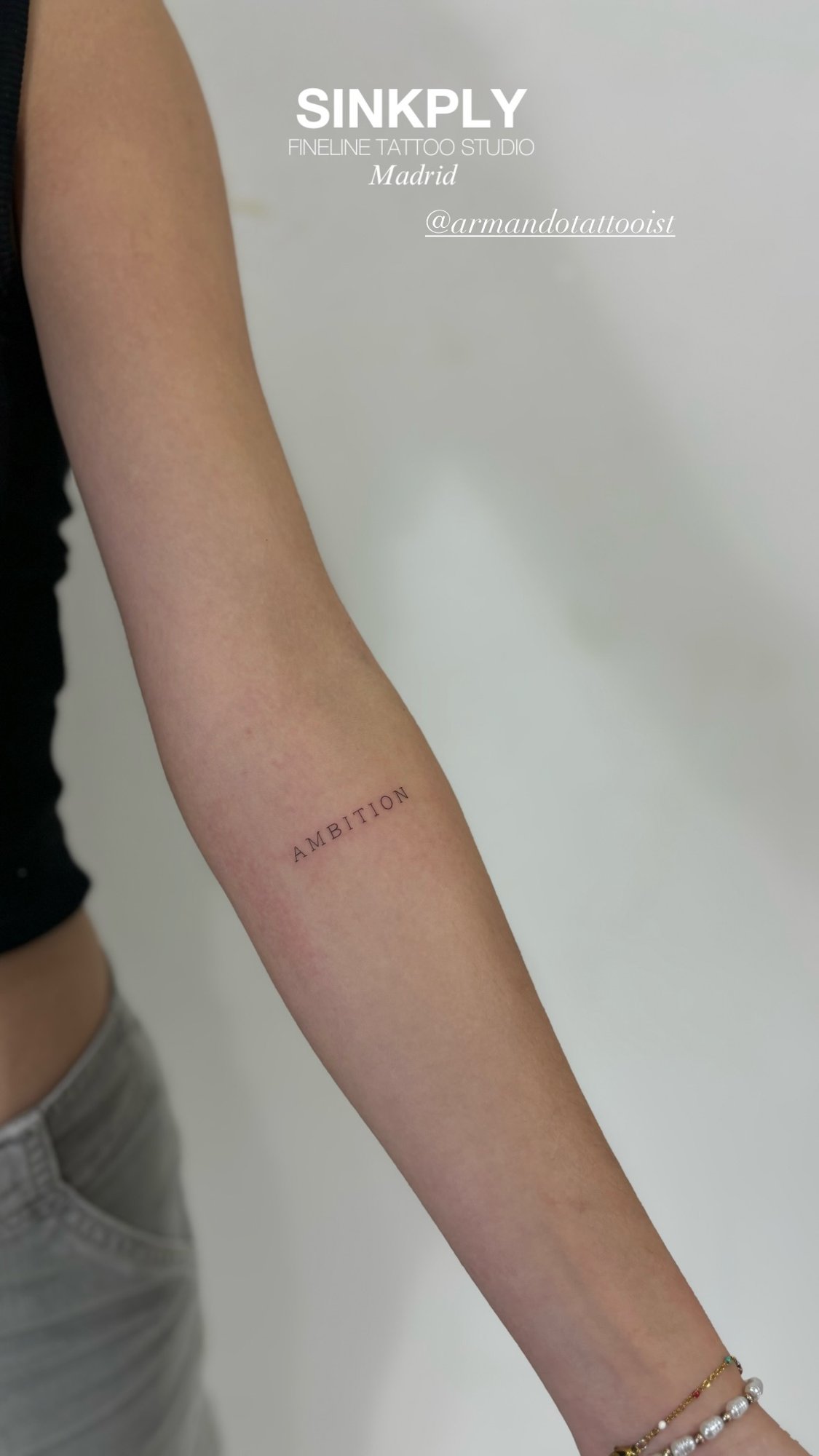 Tatuaje de palabra ambition fineline en antebrazo, línea fina