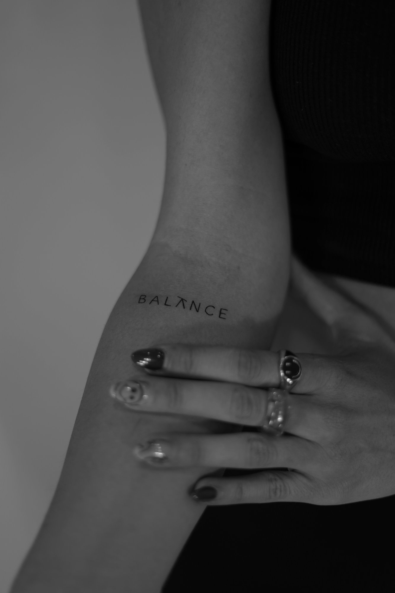 Tatuaje de palabra balance tipografia mod en antebrazo, línea fina