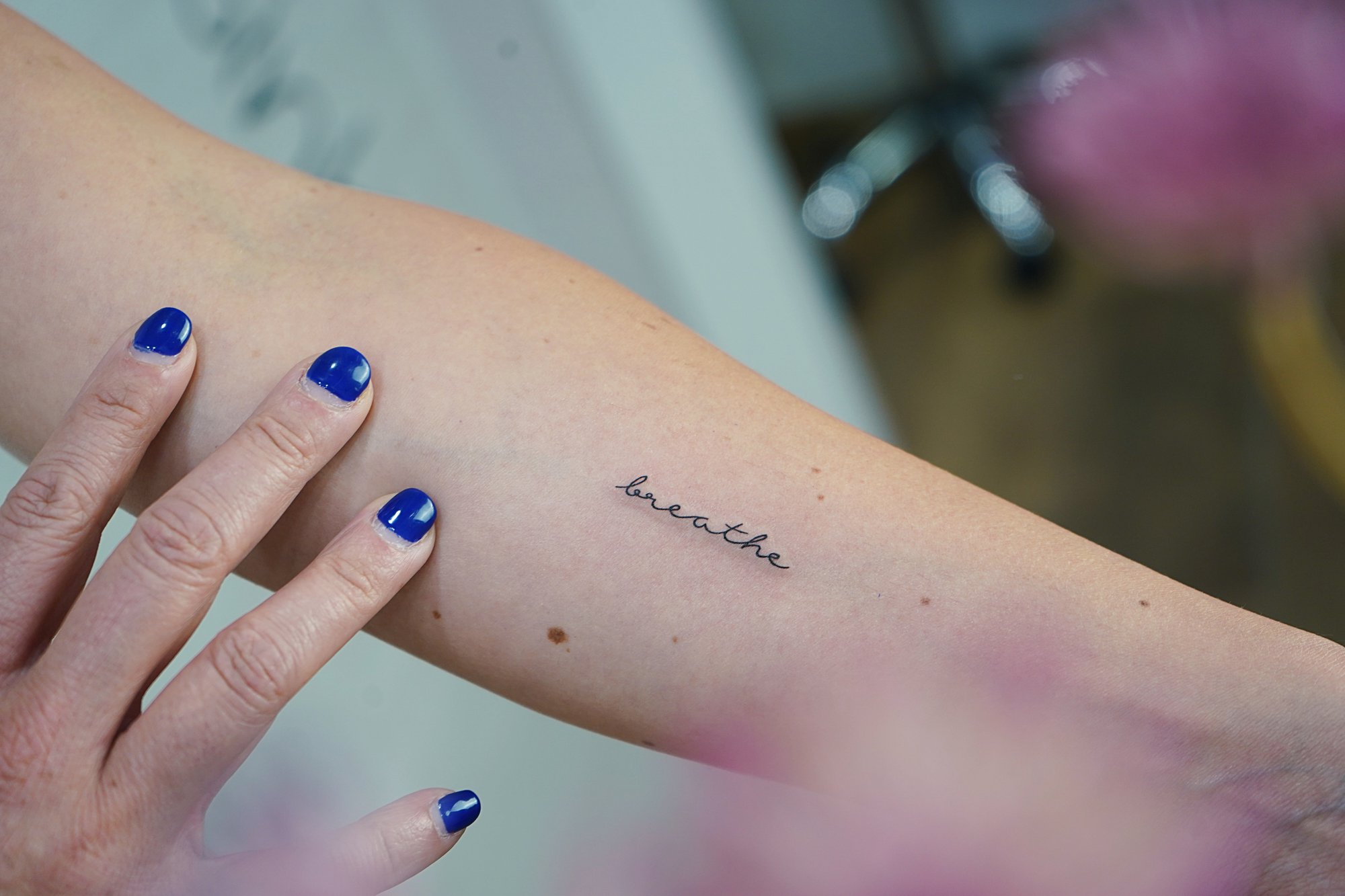 Tatuaje de palabra breathe en antebrazo, línea fina