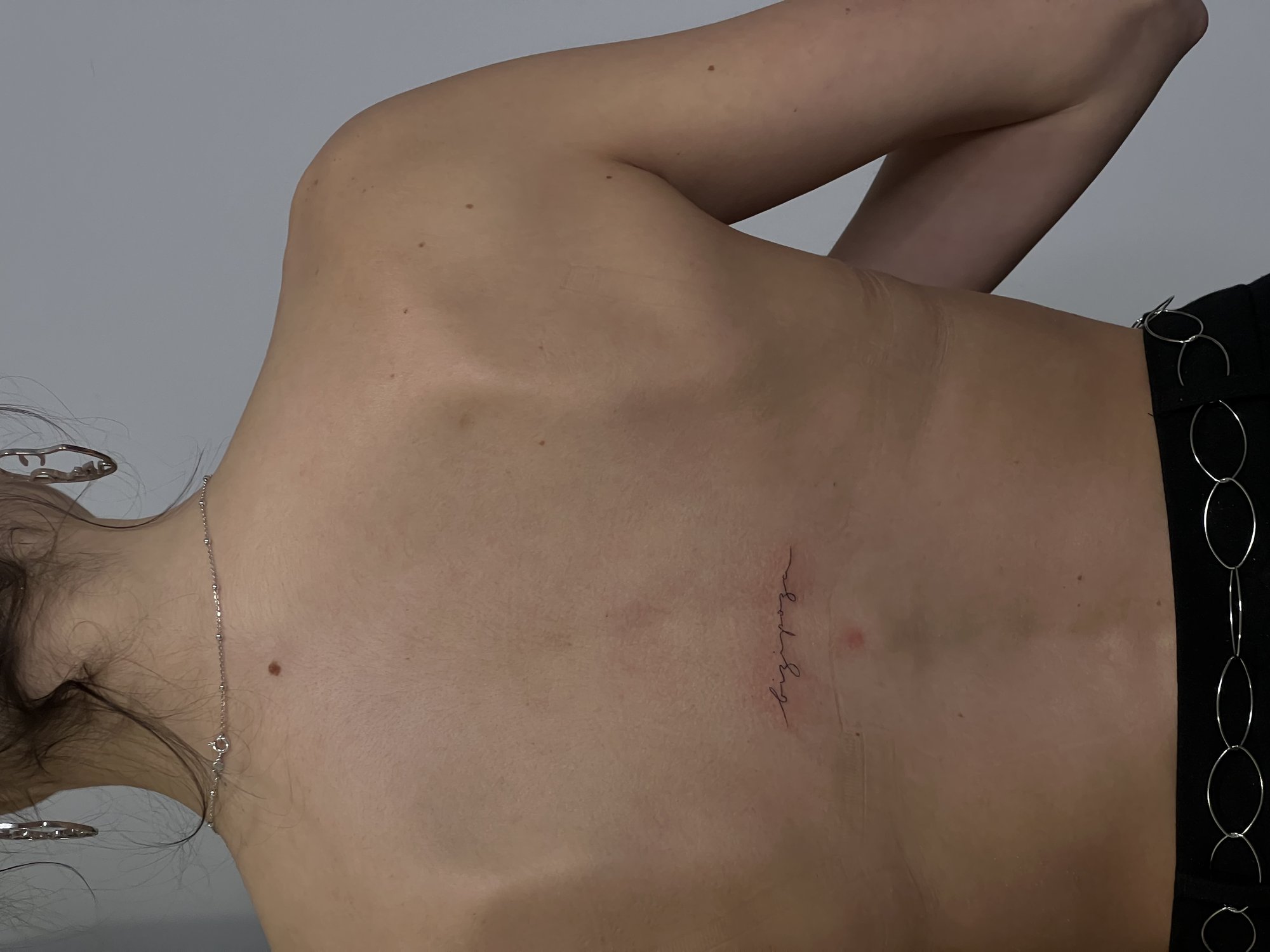 Tatuaje de palabra cursiva bizipoza espal en espalda, línea fina