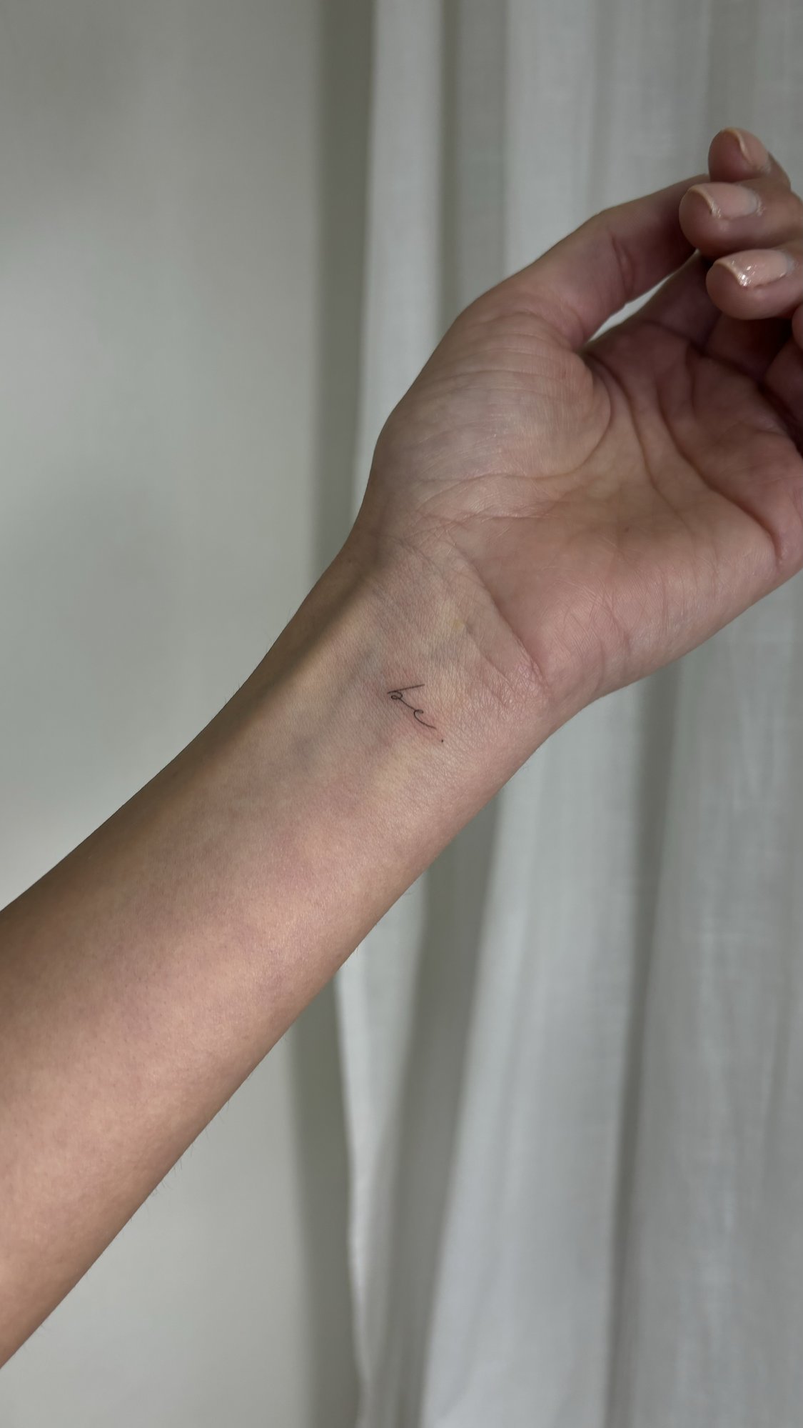 Tatuaje de palabra cursiva minimalista mu en muneca, línea fina