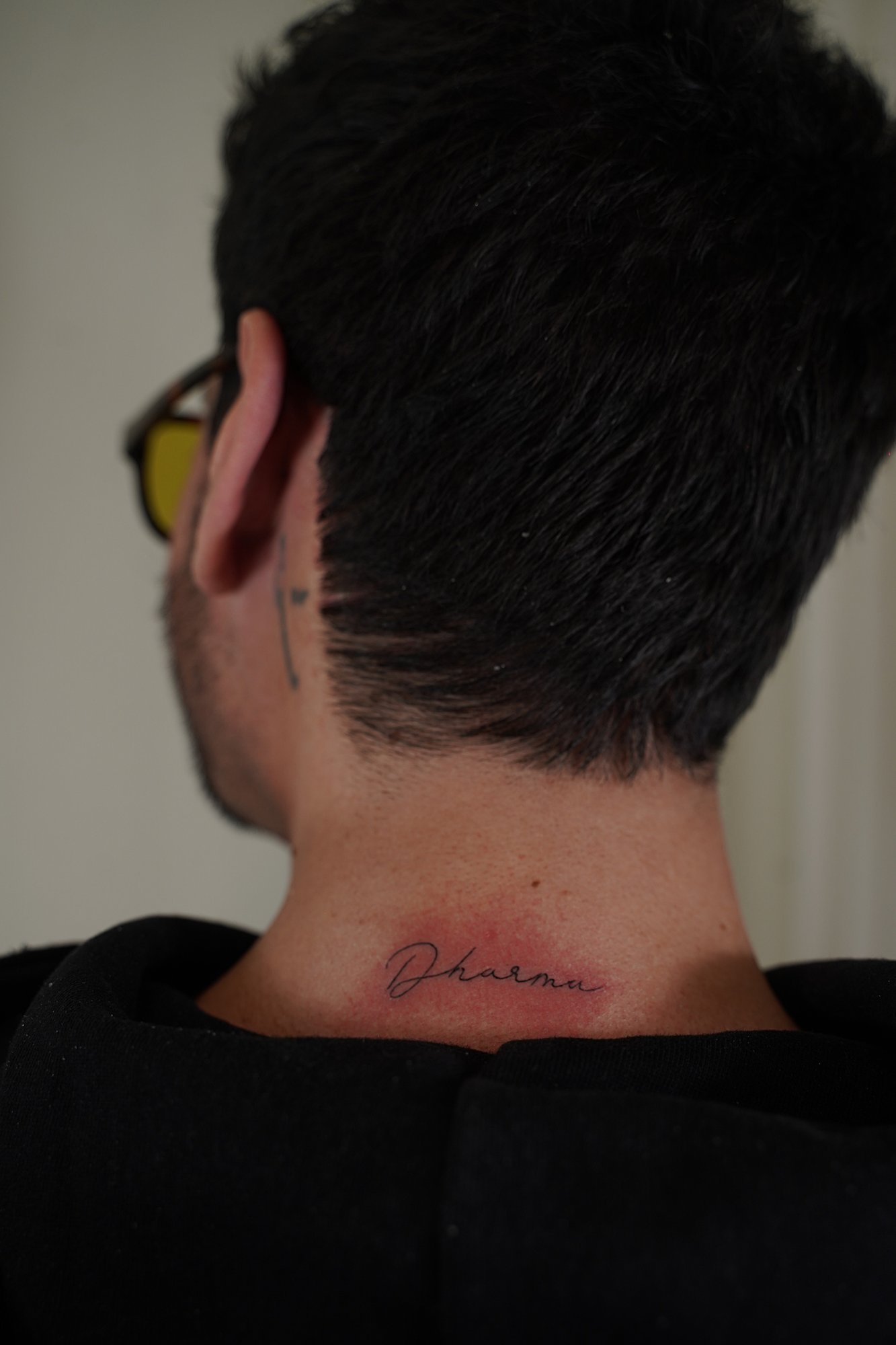 Tatuaje de palabra dharma en cuello, línea fina