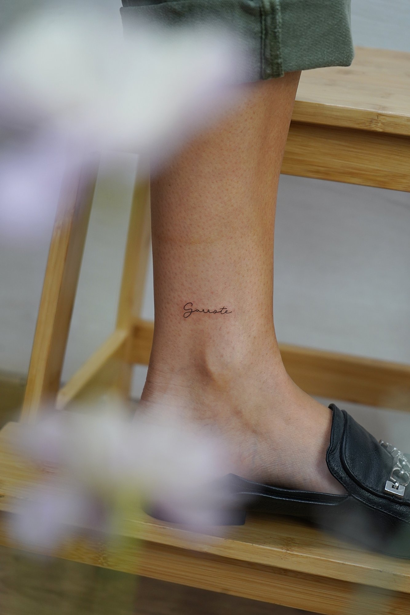 Tatuaje de palabra garrote en tobillo, línea fina