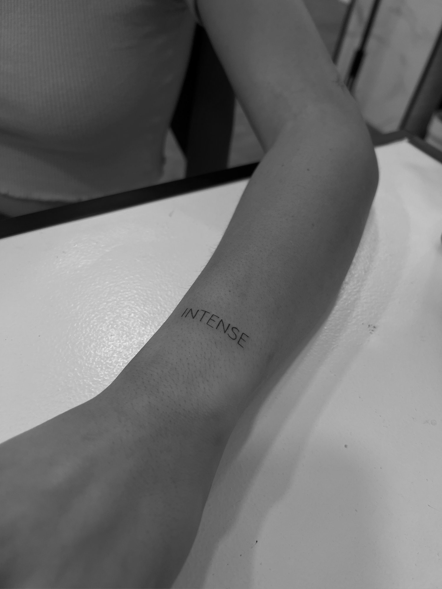 Tatuaje de palabra intense minimalista en antebrazo, línea fina