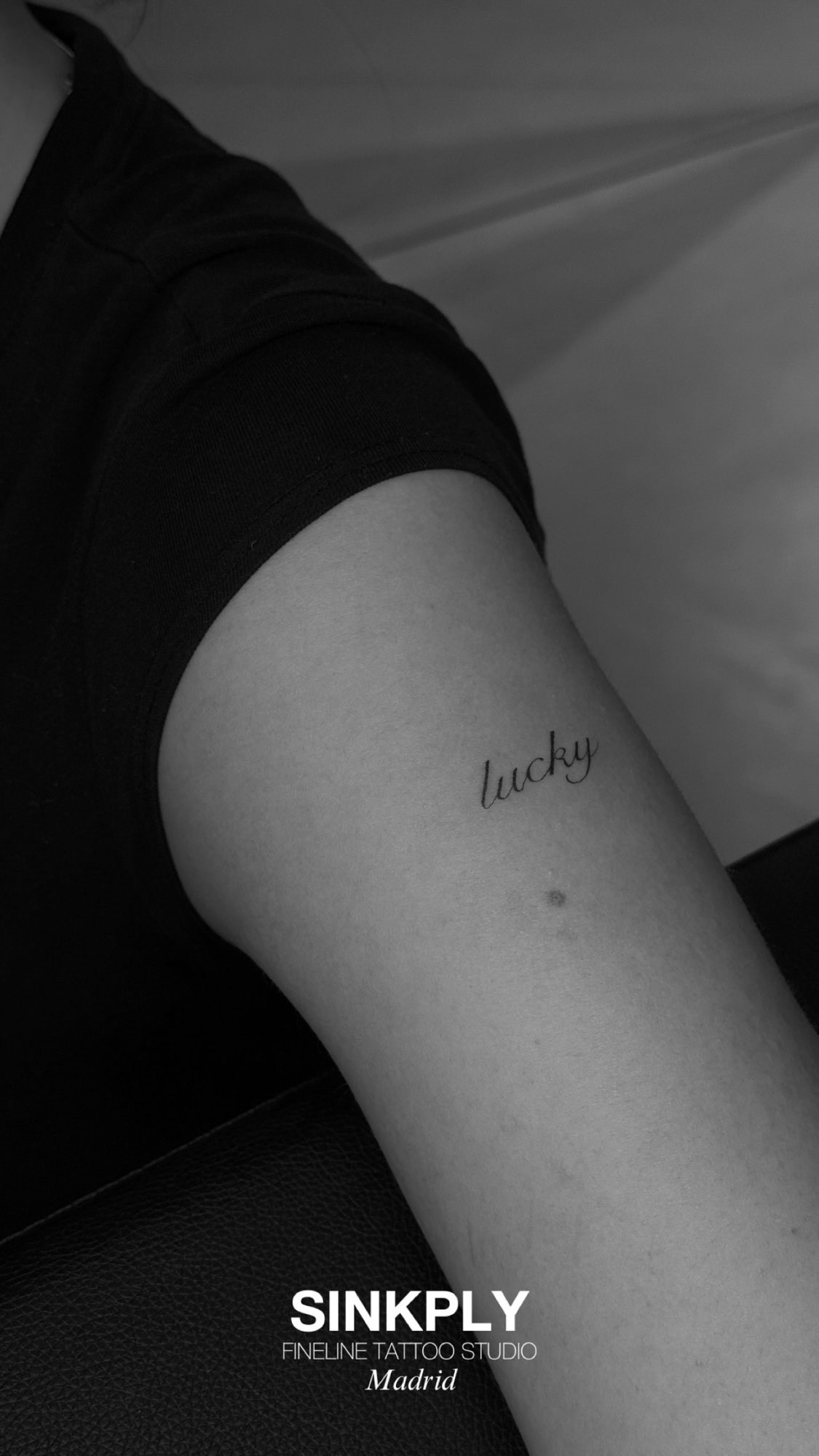 Tatuaje de palabra lucky cursiva fineline en muslo, línea fina