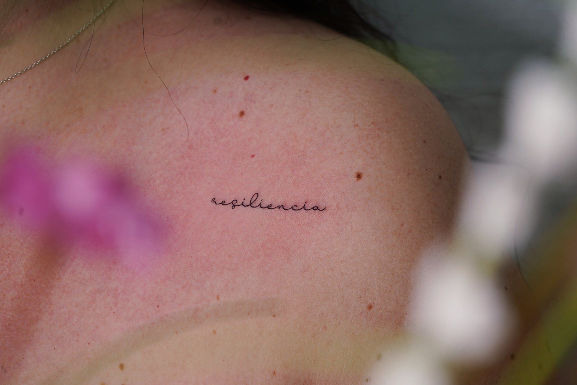 Tatuaje de palabra resiliencia en hombro, línea fina