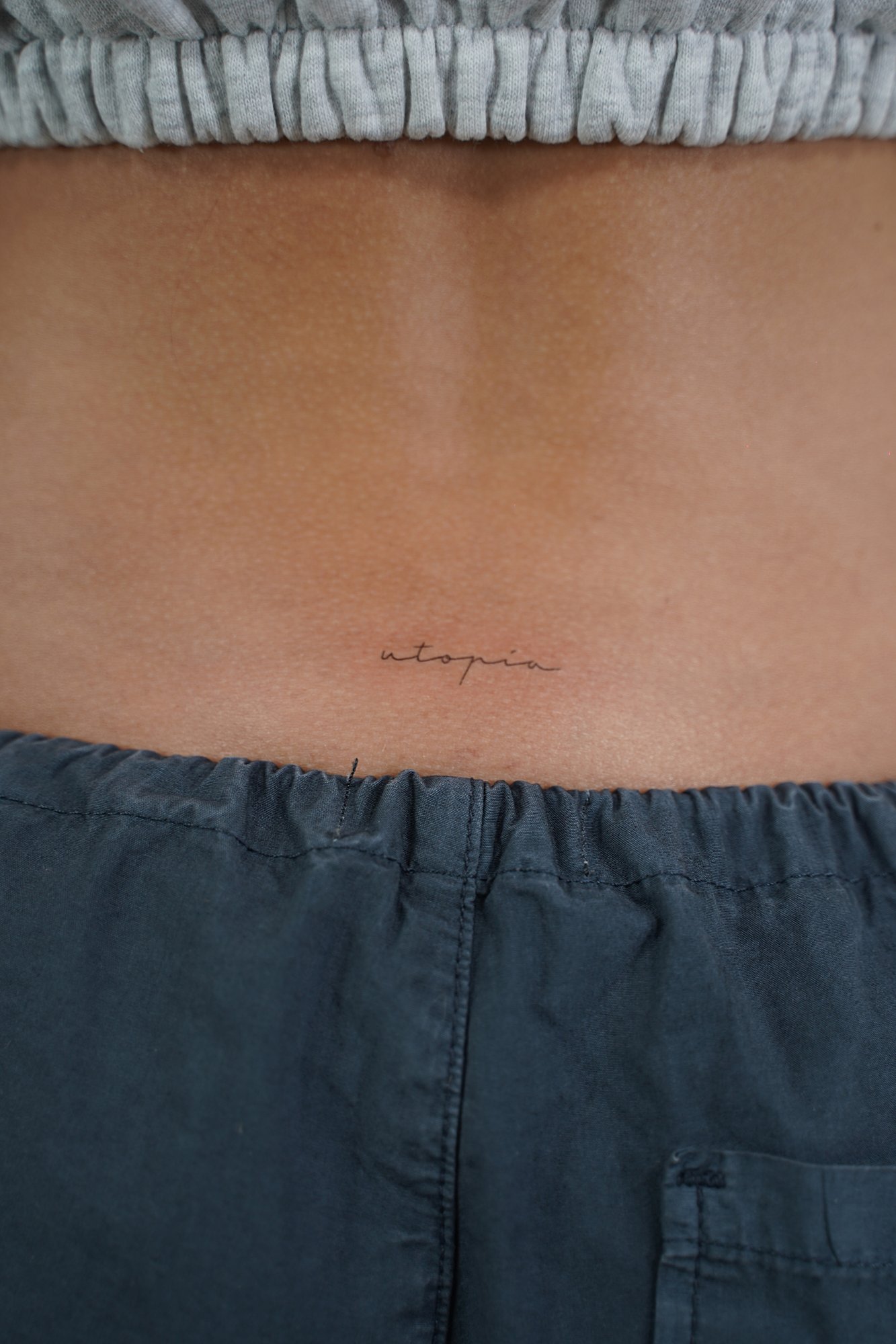 Tatuaje de palabra utopia en espalda, línea fina