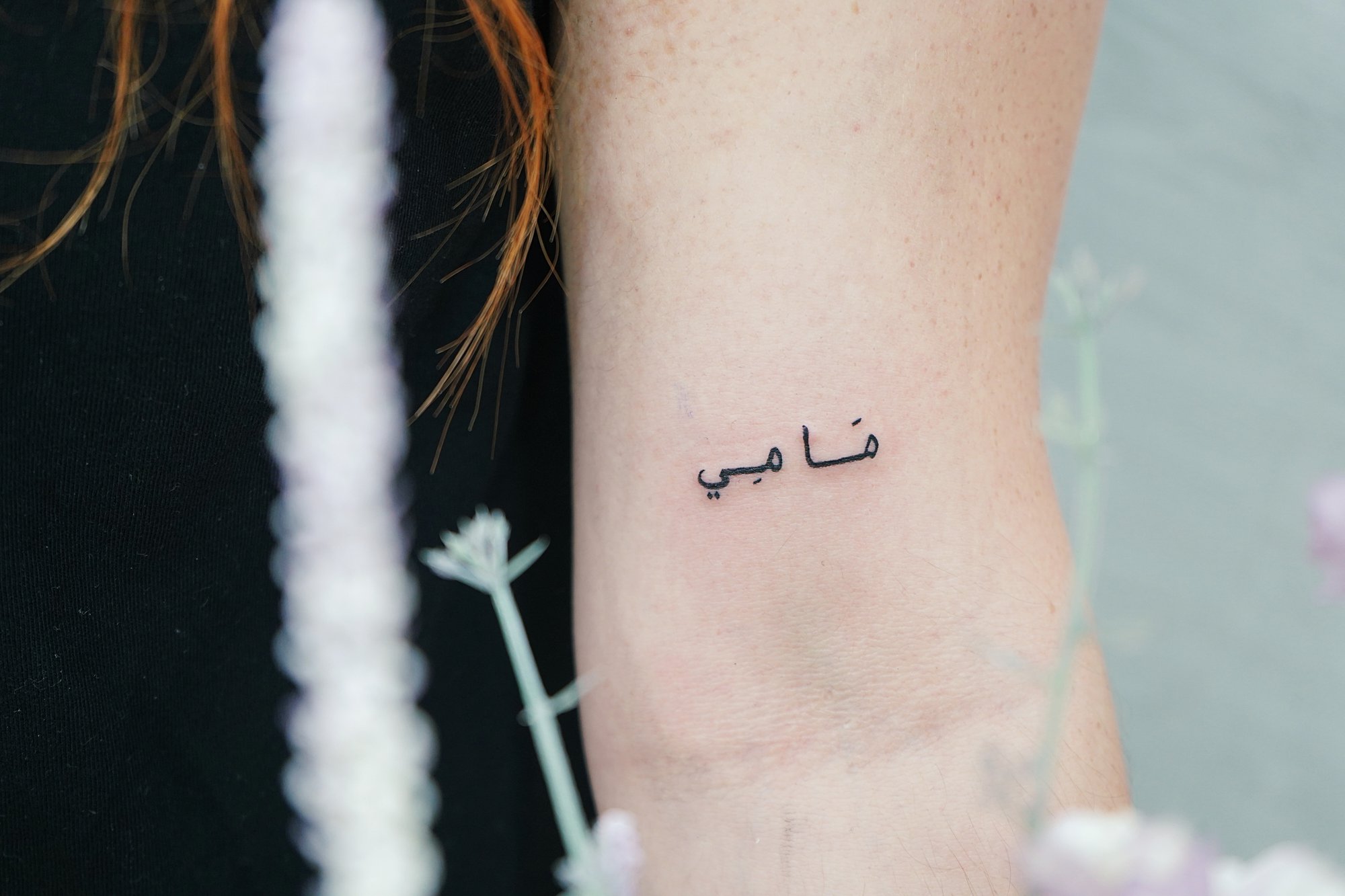 Tatuaje de palabras arabe en biceps, línea fina