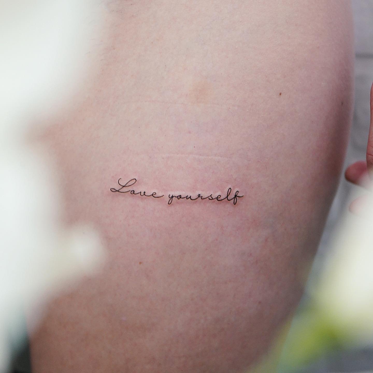 Tatuaje de frase en costilla, línea fina Sinkply Madrid