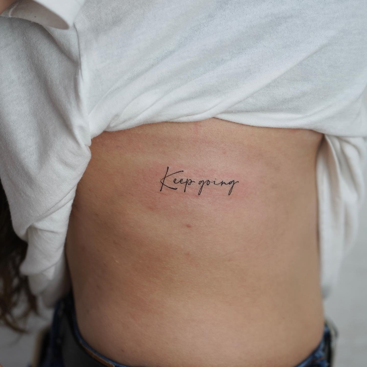 Tatuaje de frase en costilla, línea fina Sinkply Madrid