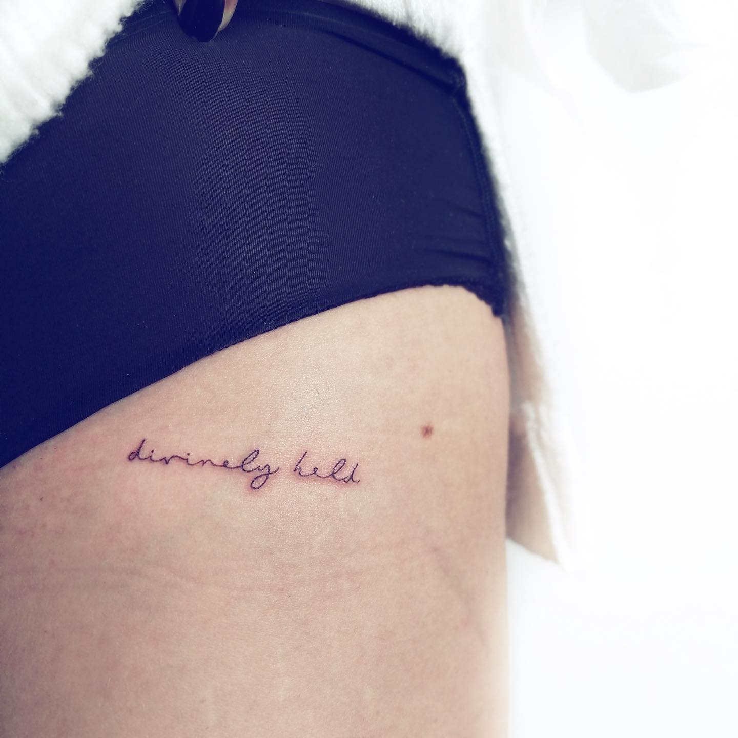 Tatuaje de frase en muslo, línea fina Sinkply Madrid