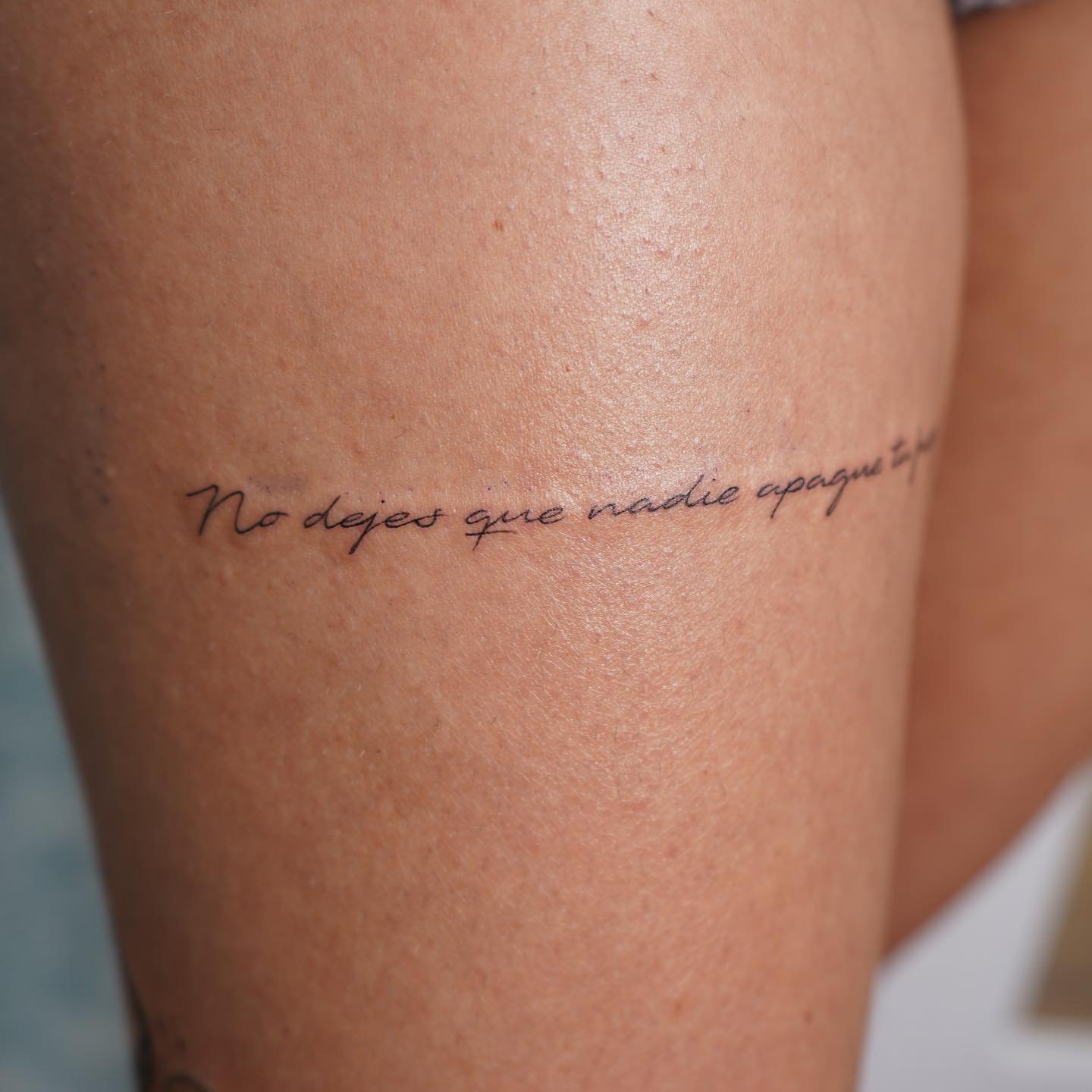 Tatuaje de frase en muslo, línea fina Sinkply Madrid