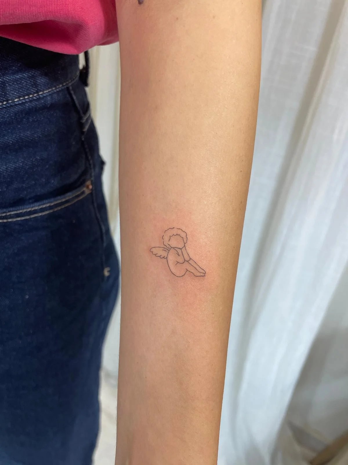 Tatuaje angel bebe sentado fine line antebrazo