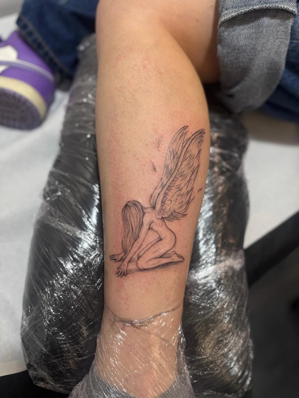 Tatuaje retrato-silueta angel sentado con alas antebrazo