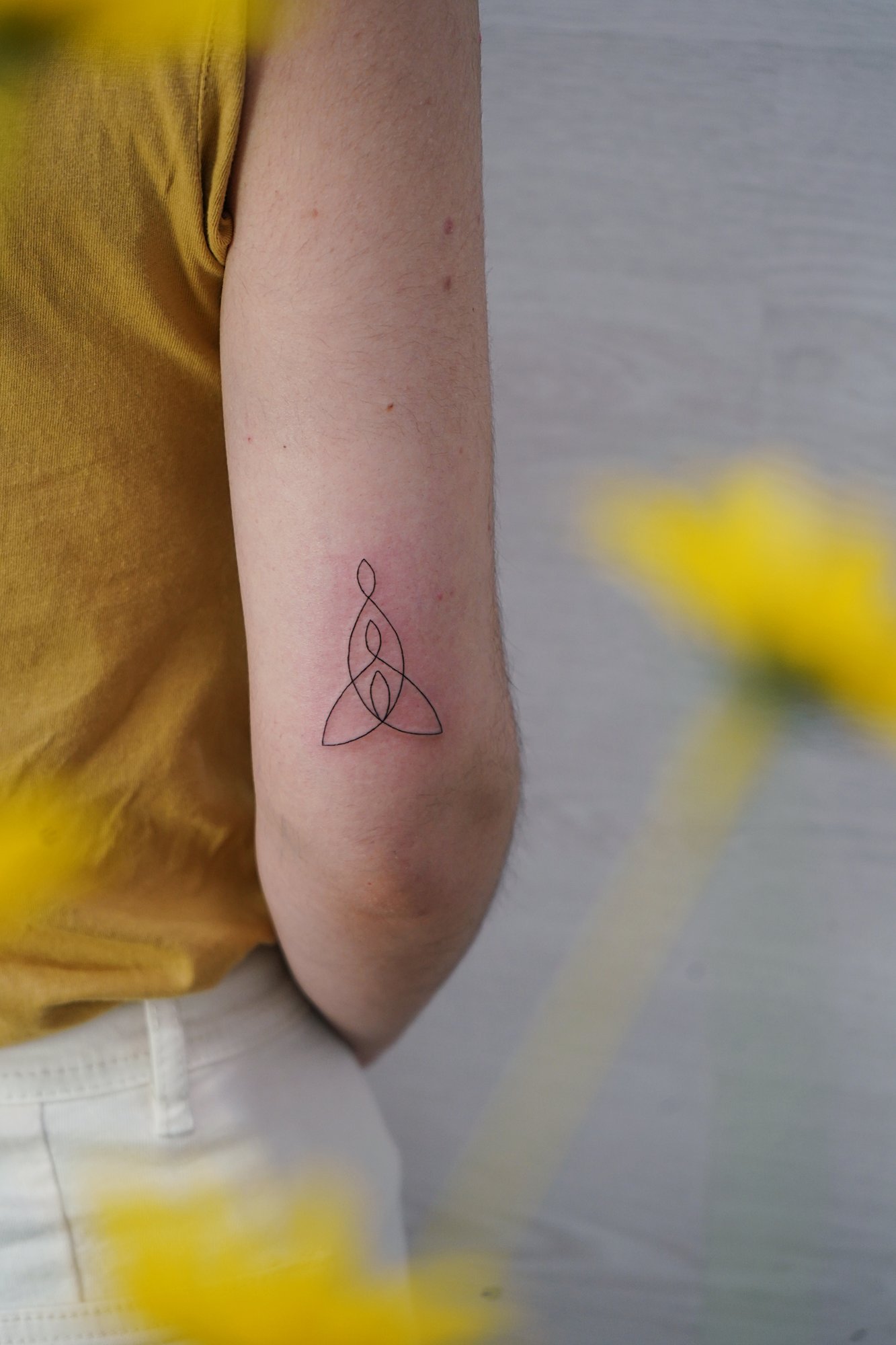 Tatuaje de tres personas en codo, línea fina