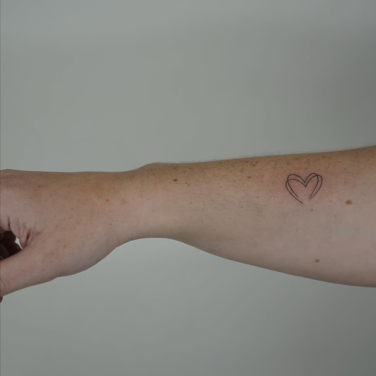 Tatuaje de corazon en antebrazo, línea fina Sinkply Madrid