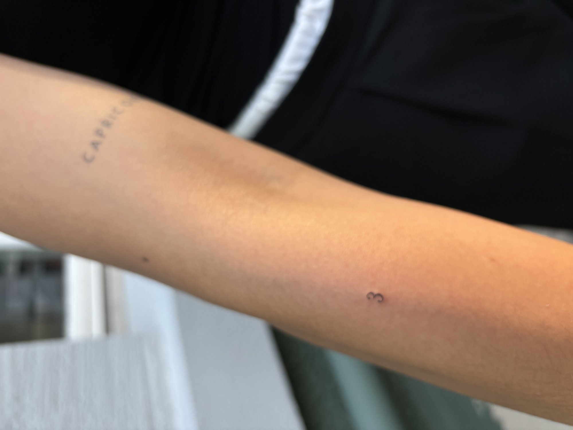 Tatuaje de capricorn texto y numero 3 en antebrazo, línea fina