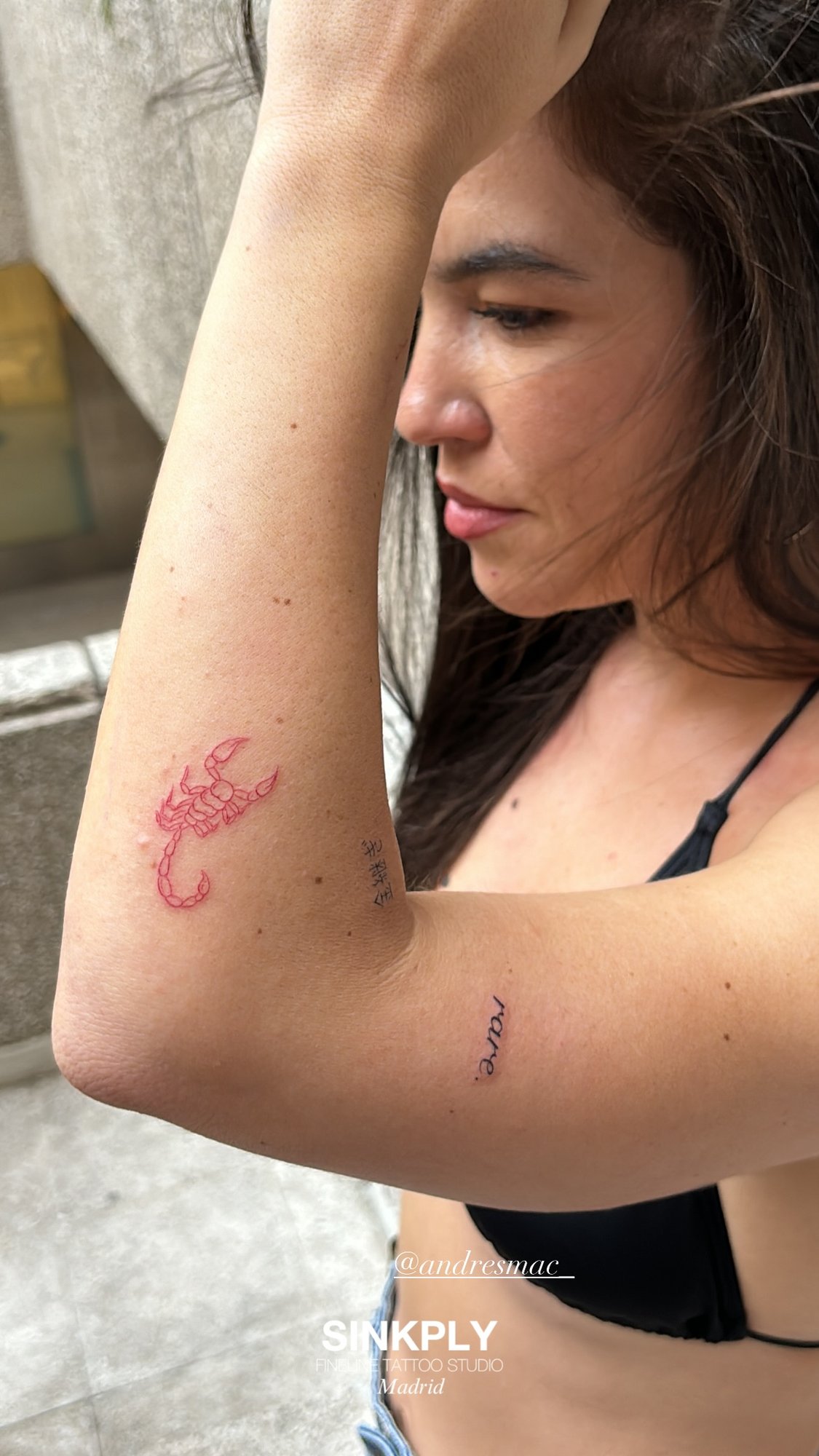 Tatuaje de escorpion rojo y letras en brazo, línea fina