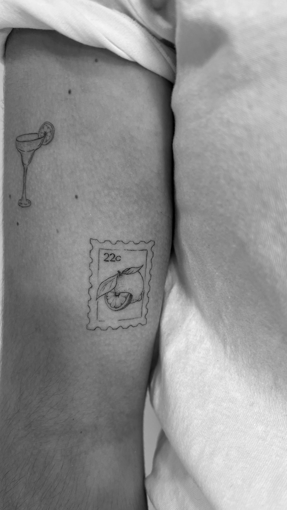 Tatuaje de estampilla citrico y coctel en antebrazo, línea fina