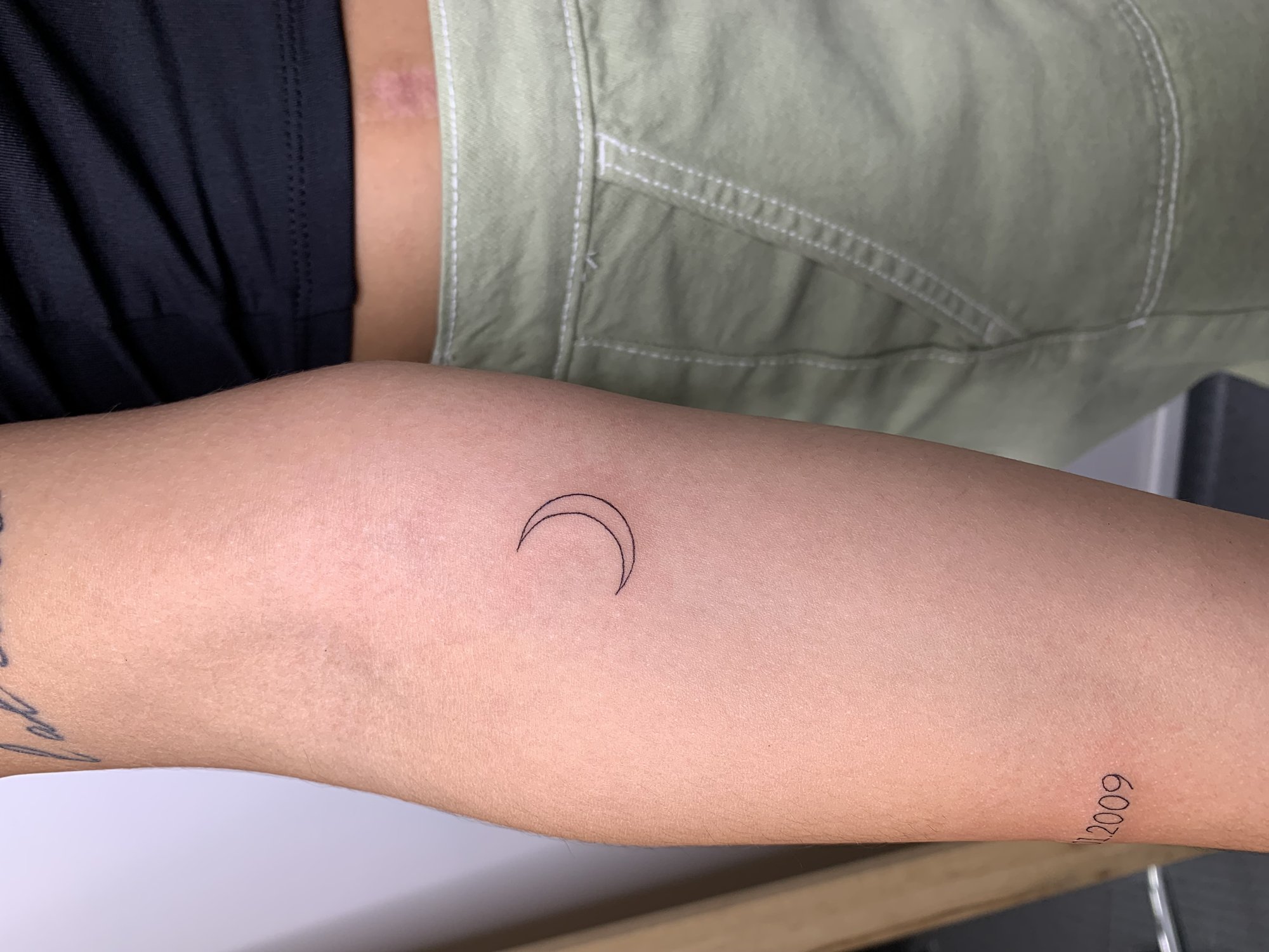 Tatuaje de luna creciente y fecha en antebrazo, línea fina