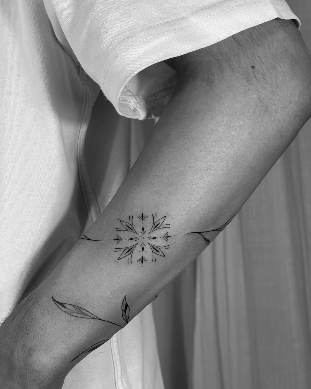 Tatuaje de mandala floral con hojas en brazo, línea fina
