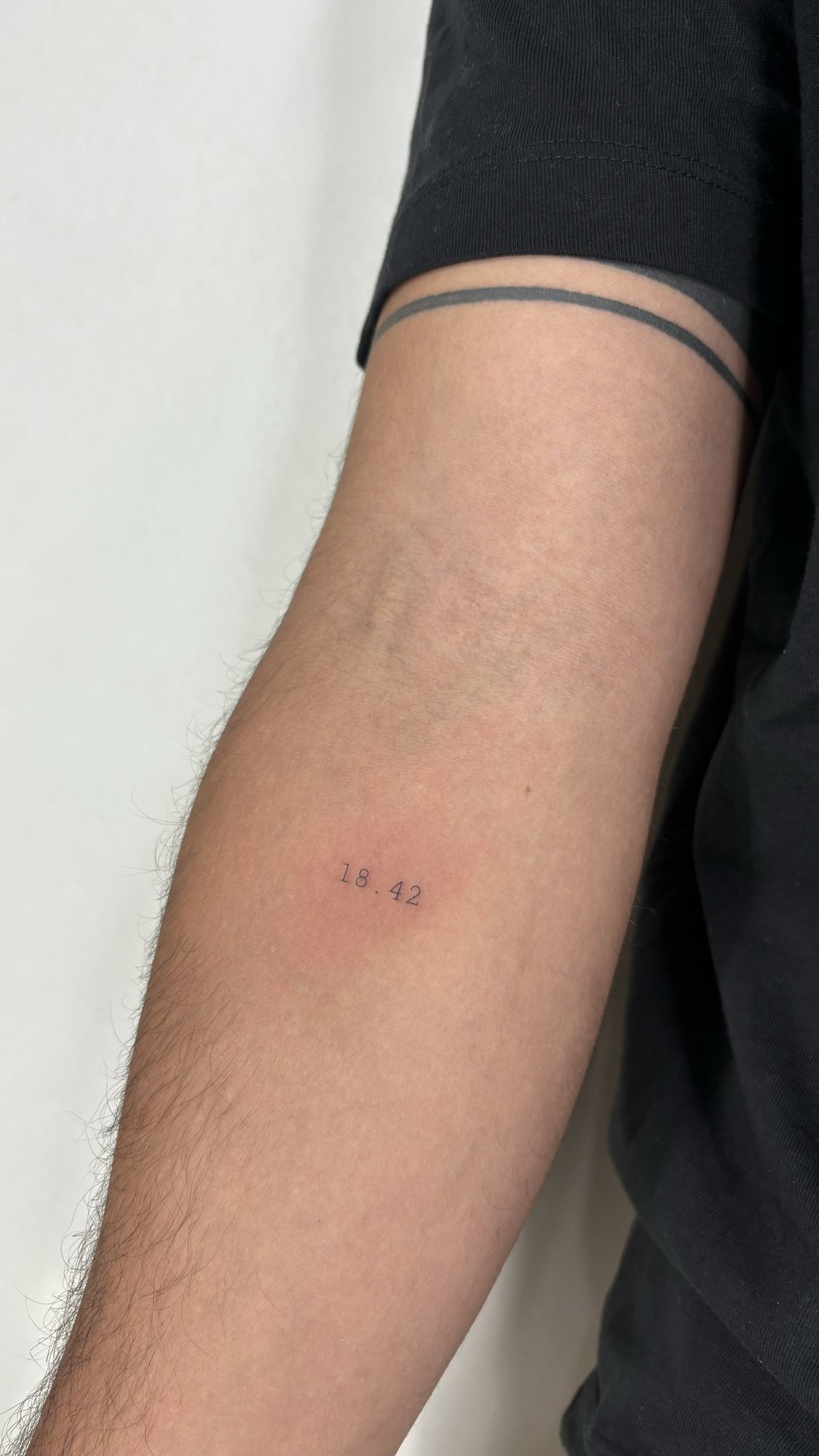 Tatuaje de numeros 18.42 y linea brazo en brazo, línea fina