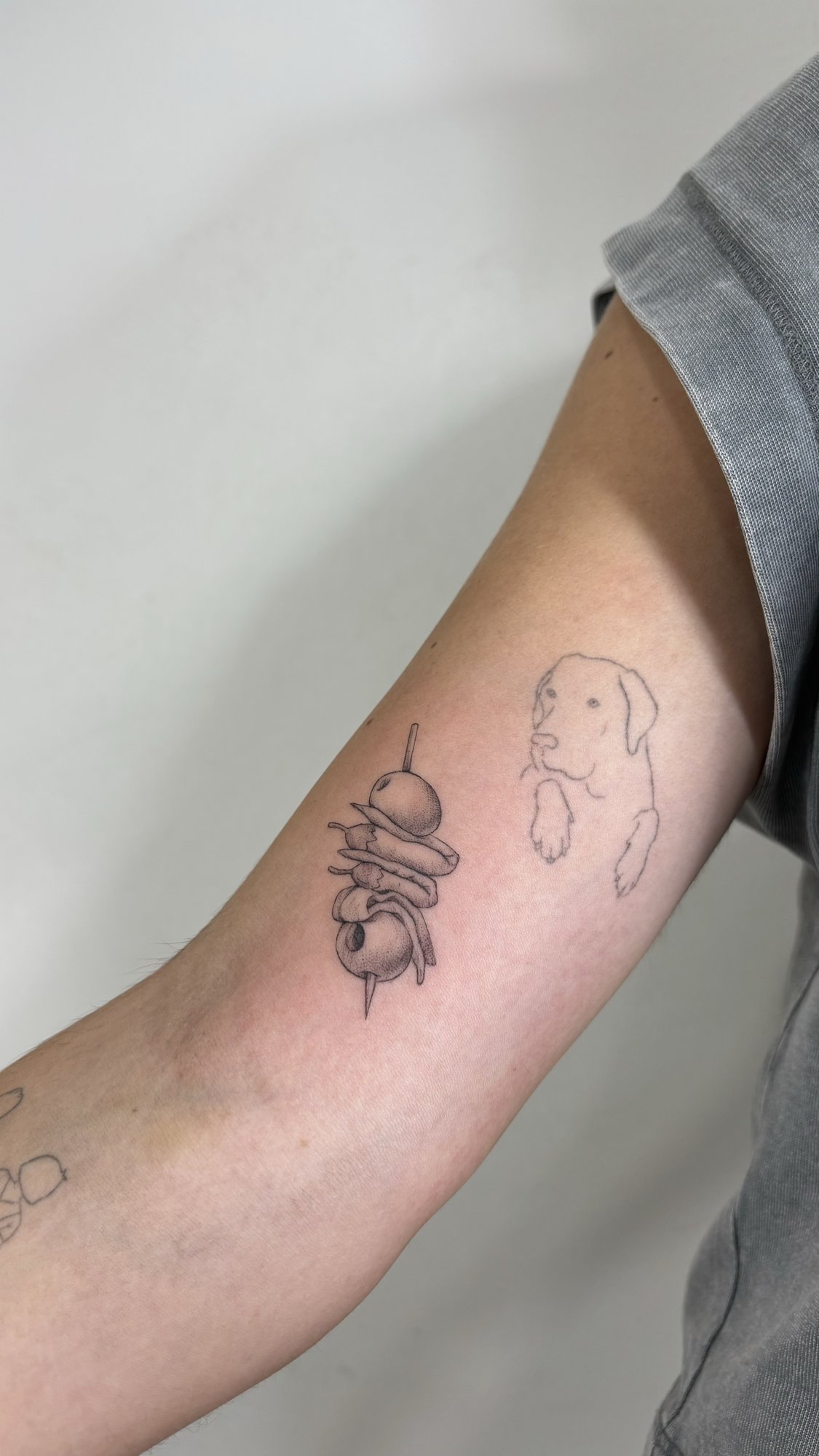Tatuaje de pintxo y perro minimalista en brazo, línea fina