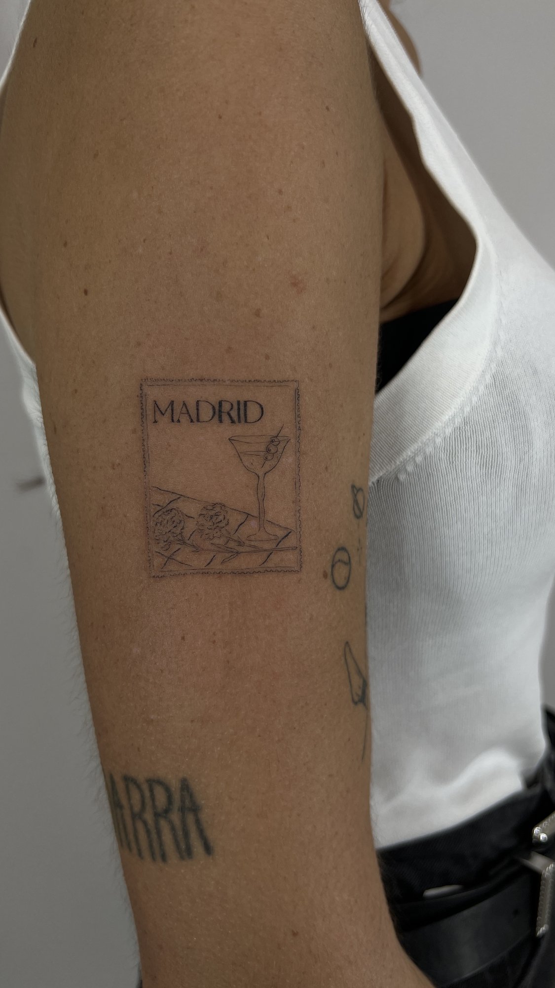 Tatuaje de postal madrid cocktail letras en brazo, línea fina